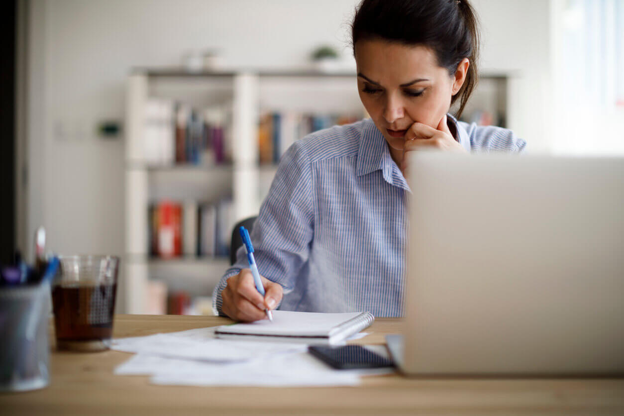 Woman sitting at a desk and writing on a notebook