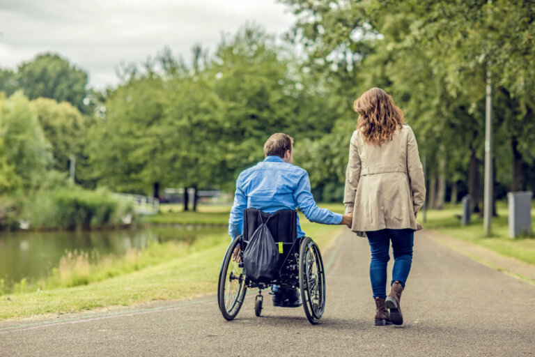 Man on a wheelchair walking with a woman at the park