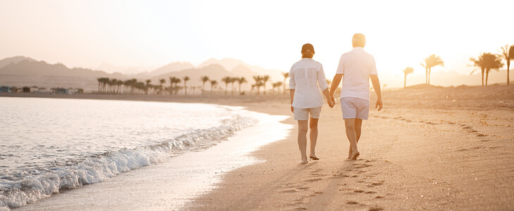 Man and woman walking on the beach at sunset