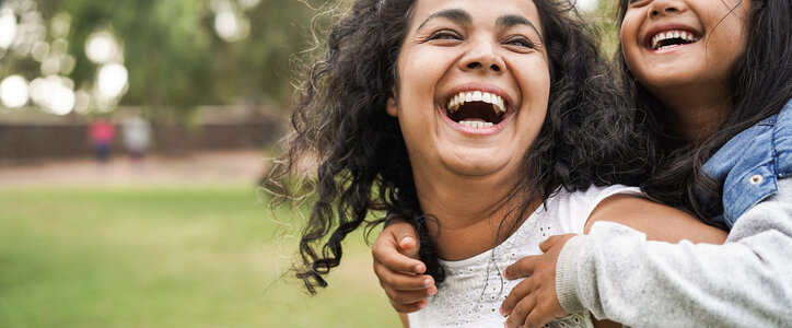 Happy mother giving her daughter a piggyback ride.