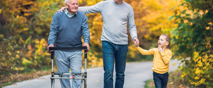 Elderly father adult son and grandson out for a walk in the park.