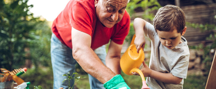 Grandfather and grandson playing in backyard with gardening tools