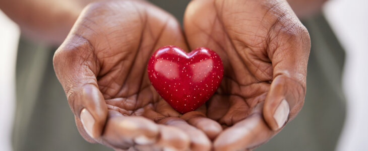Close up of black woman hands holding a small red heart. Small heart in the hands of a african woman. Solidarity, charity and responsibility concept.